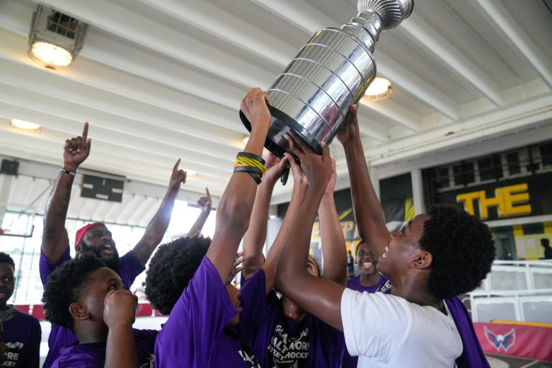 kids hoist trophy in the air, smiling and lifting arms up