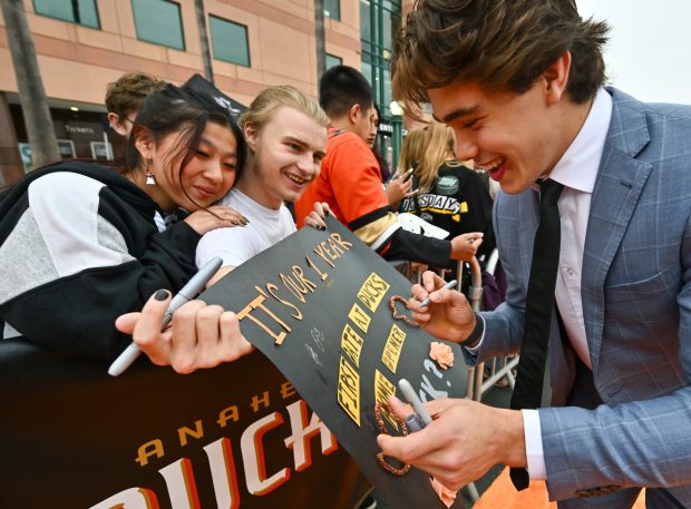 Ducks defenseman Olen Zellweger signs a poster for Gisele Matoca,...