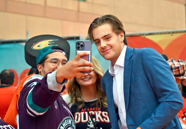 Ducks forward Leo Carlsson, right, takes a selfie with fans...