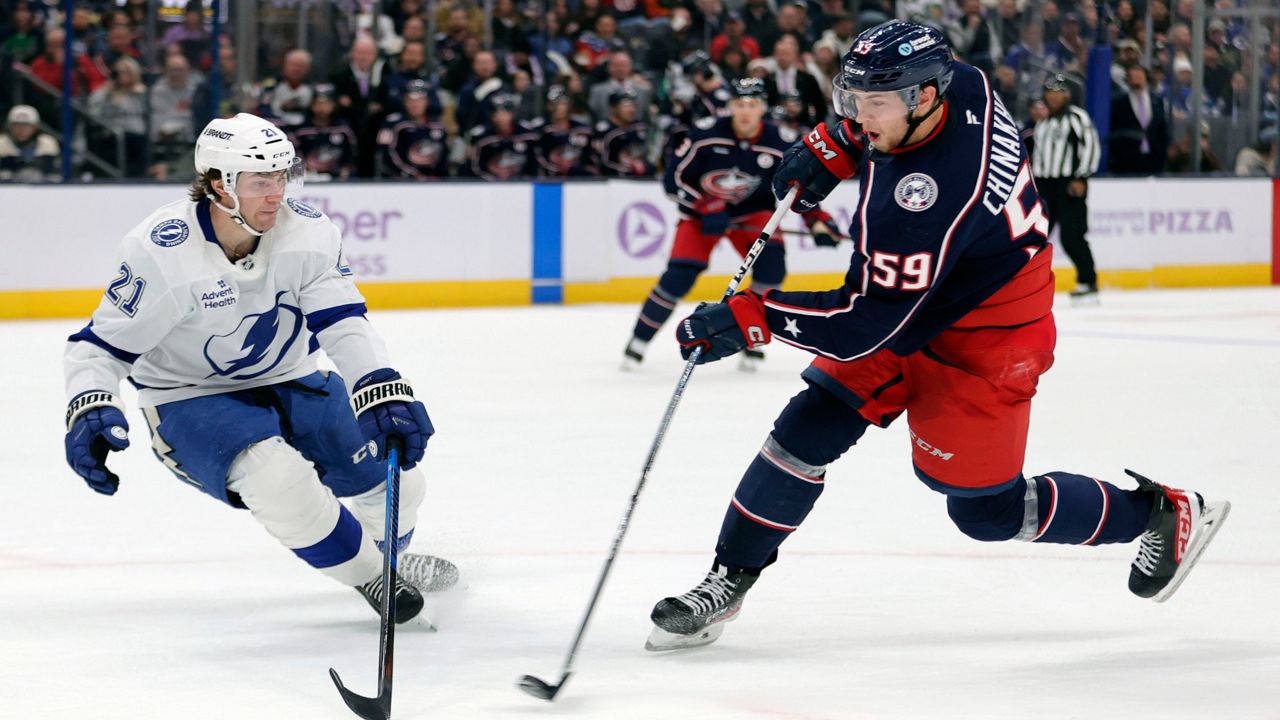 Tampa Bay Lightning forward Brayden Point, left, tries to block a shot by Columbus Blue Jackets forward Yegor Chinakhov, right, during the second period of an NHL hockey game in Columbus, Ohio, Thursday, Nov. 21, 2024.