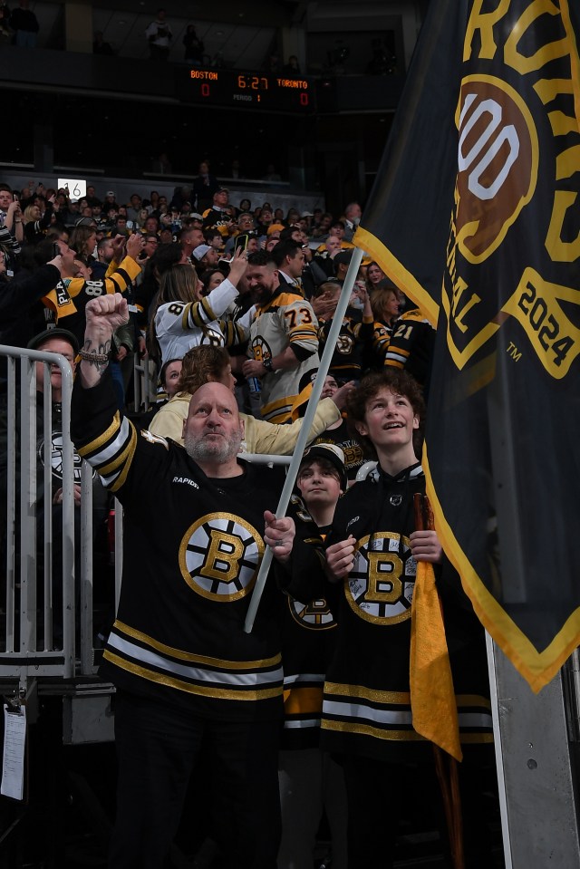 Lyndon Byers, former Boston Bruins player, waves a team flag at a hockey game.