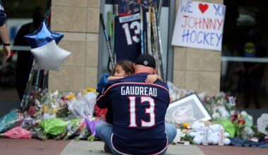 Shiloh Rivera, facing, mourns with Hylas Stemen of Columbus, at the makeshift memorial set up by fans for Blue Jackets hockey player Johnny Gaudreau in Columbus, Ohio, Friday, Aug. 30, 2024. Gaudreau, along with his brother Matthew, was fatally struck by a motorist while riding his bicycle on Thursday. (AP Photo/Joe Maiorana)