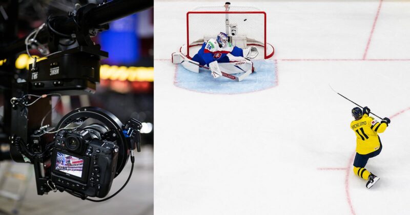 Close-up of a professional camera capturing a hockey game; next to it, a hockey player in yellow shoots the puck towards the goal as the opposing goalie makes a save attempt on the ice.