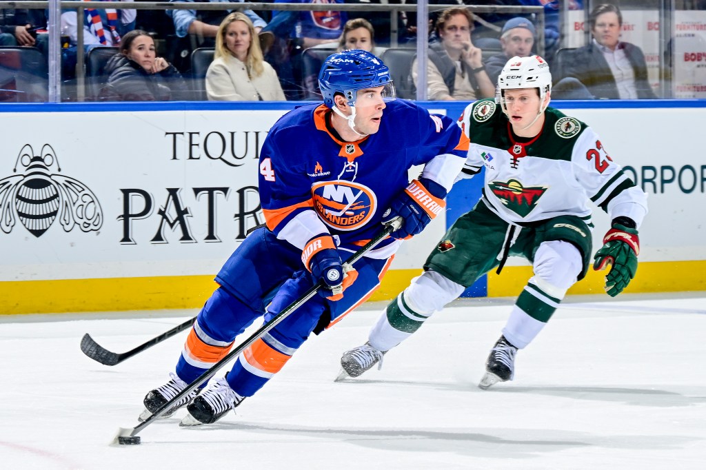 New York Islanders' Tony DeAngelo #4 skating with the puck, defended by Minnesota Wild player.