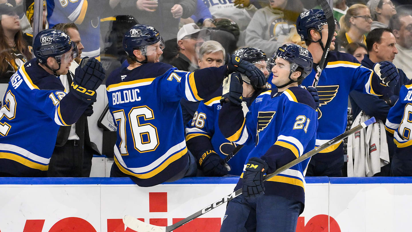 Apr 3, 2025; St. Louis, Missouri, USA;  St. Louis Blues right wing Jimmy Snuggerud (21) is congratulated by teammates after assisting on a goal by left wing Jake Neighbours (not pictured) for his first NHL point during the third period against the Pittsburgh Penguins at Enterprise Center. Mandatory Credit: Jeff Curry-Imagn Images