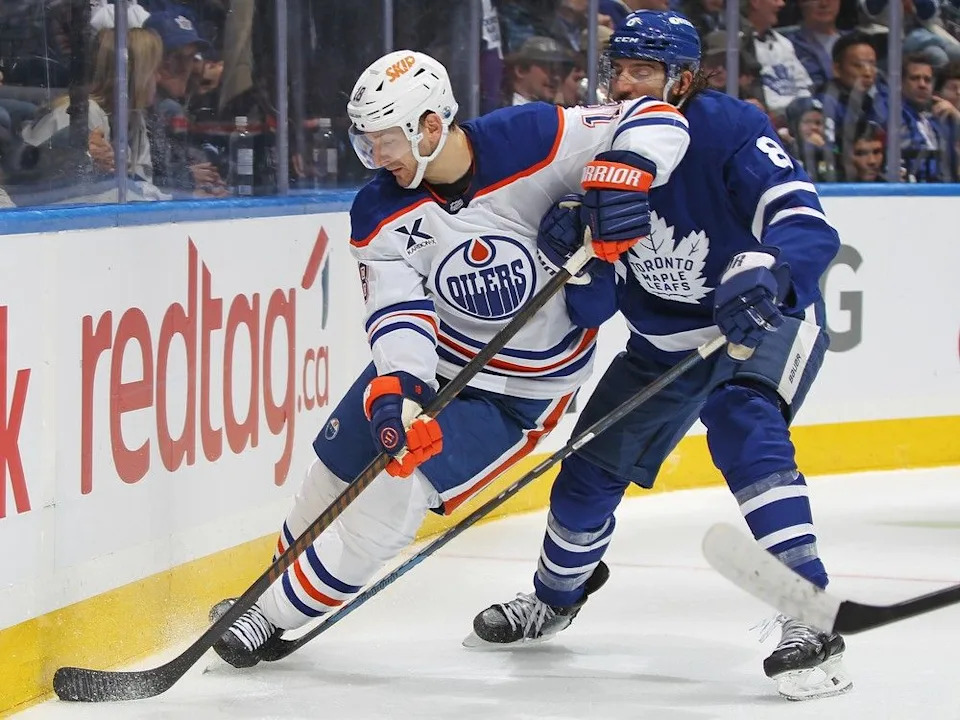 Zach Hyman #18 of the Edmonton Oilers skates with the puck against Christopher Tanev #8 of the Toronto Maple Leafs during the third period in an NHL game at Scotiabank Arena on Nov. 16, 2024 in Toronto. The Maple Leafs defeated the Oilers 4-3 in overtime.