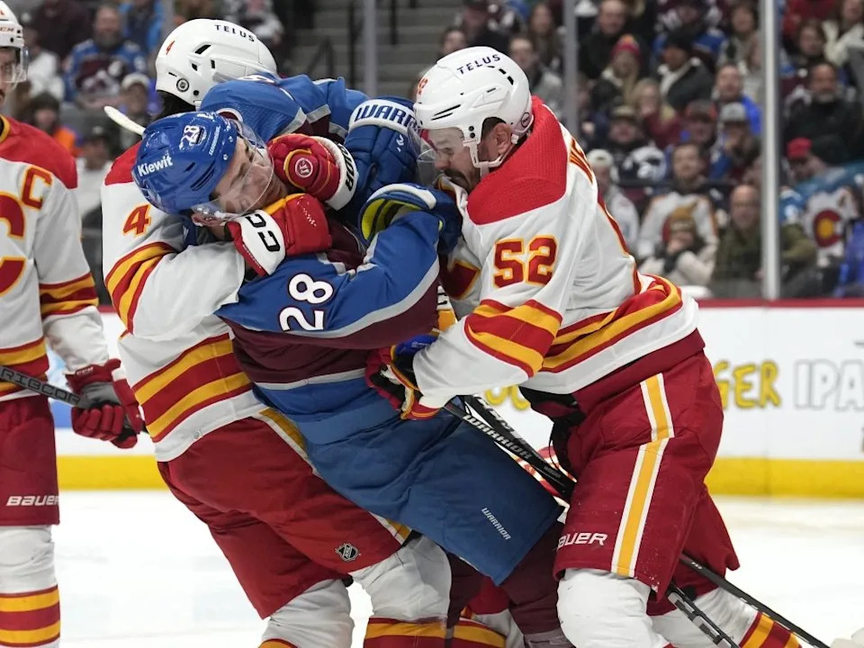 Colorado Avalanche forward Miles Wood is sandwiched between Flames defencemen Rasmus Andersson and MacKenzie Weegar.