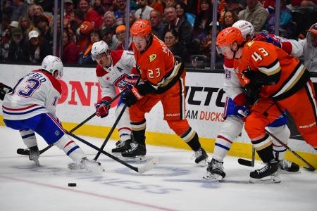 Feb 2, 2025; Anaheim, California, USA;Anaheim Ducks center Mason McTavish (23) and defenseman Drew Helleson (43) play for the puck against Montreal Canadiens right wing Cole Caufield (13) and right wing Brendan Gallagher (11) during the third period at Honda Center. Mandatory Credit: Gary A. Vasquez-Imagn Images