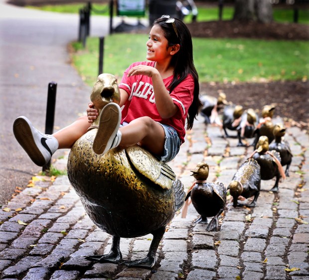 Jaznine Quispe, 11, poses for her mother at the popular Make Way for Ducklings statue at the Boston Public Garden. (Mark Stockwell/Boston Herald)
