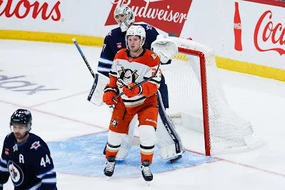 Anaheim Ducks forward Mason McTavish screens Winnipeg Jets goaltender Connor Hellebuyck during 2025 game.