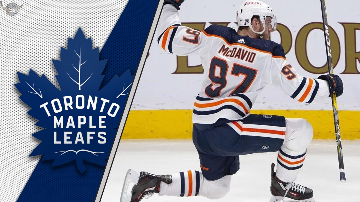 Connor McDavid celebrates a goal during a game, with the Toronto Maple Leafs logo in the background, fueling NHL rumors of a potential trade.