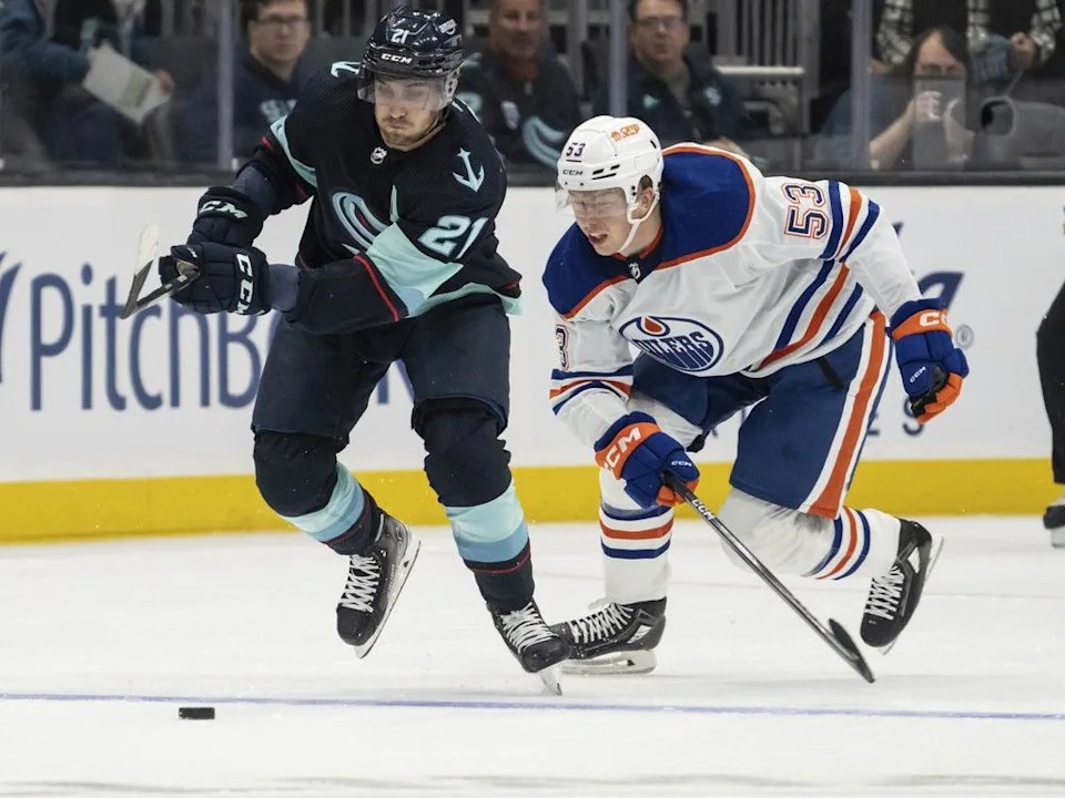  Seattle Kraken forward Alex Wennberg and Edmonton Oilers forward Reid Schaefer battle for the puck during the first period of a preseason NHL hockey game, Monday, Sept. 26, 2022, in Seattle.