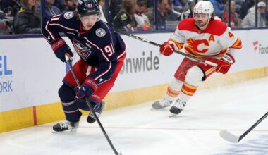 Columbus Blue Jackets forward Kent Johnson, left, controls the puck in front of Calgary Flames defenseman Rasmus Andersson during an NHL hockey game in Columbus, Ohio, Friday, Nov. 29, 2024. The Blue Jackets won 5-2. (AP Photo/Paul Vernon)