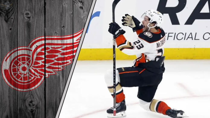 mason-mctavish-red-wings-2025 Detroit Red Wings logo to the left, with a photo of Mason McTavish to the right, illustrating the latest NHL trade rumors.