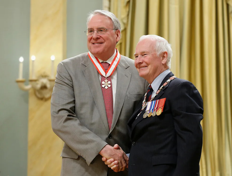 Former Member of Parliament and Canadian hockey great Ken Dryden (L) shakes hands with Governor General David Johnston after being awarded the rank of Officer in the Order of Canada.