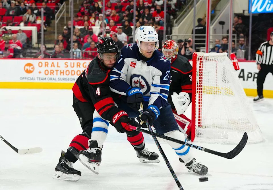 Carolina Hurricanes defenseman Shayne Gostisbehere (4) and Winnipeg Jets left wing Nikolaj Ehlers (27) battle over the puck during the second period at Lenovo Center.