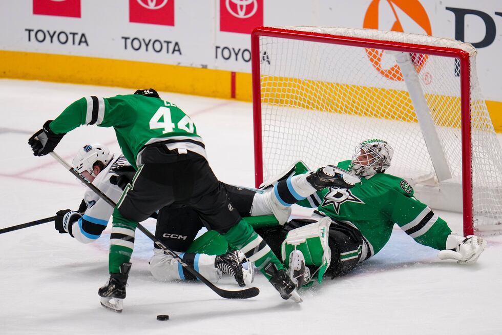 Utah Hockey Club center Barrett Hayton, center, trips over Dallas Stars goaltender Casey...