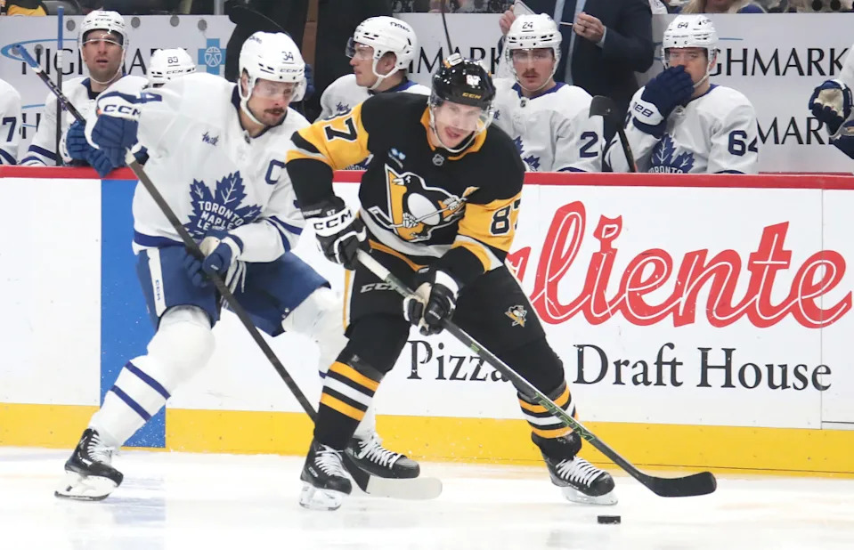 Penguins center Sidney Crosby (87) moves the puck ahead of Maple Leafs center Auston Matthews (34).© Charles LeClaire-Imagn Images