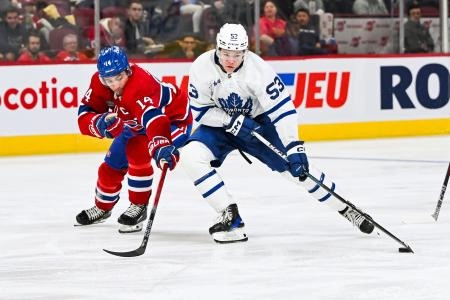 Toronto Maple Leafs forward Easton Cowan stick handling past Montreal Canadiens forward Nick Suzuki.