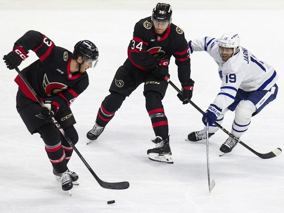  Toronto Maple Leaf Calle Jarnkrok tries to get the puck from Ottawa Senator Tyler Kleven with Arthur Kaliyev looking on as the Senators host the Leafs in preseason action at the Canadian Tire Centre on Sunday, Sept. 21, 2025.