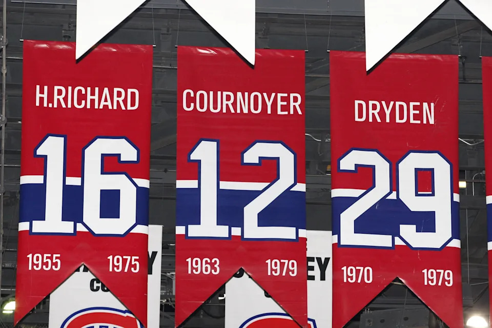 A photo of the banners commemorating the retired jerseys of Henri Richard, Yvan Cournoyer and Ken Dryden hanging in the Bell Centre.