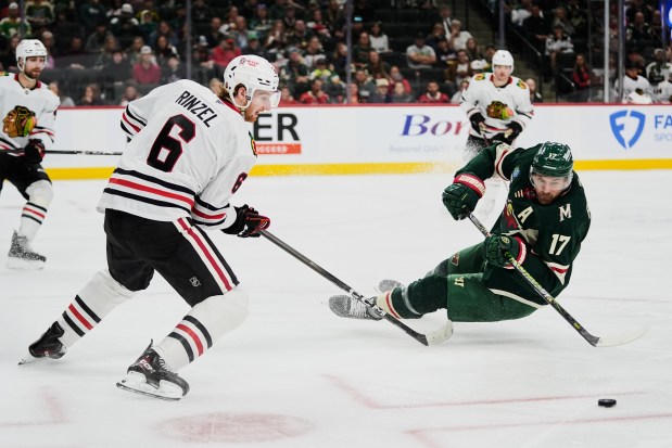 Minnesota Wild left wing Marcus Foligno (17) reaches for the puck as Chicago Blackhawks defenseman Sam Rinzel (6) applies pressure during the third period of an NHL hockey preseason game, Sunday, Sept. 28, 2025, in St. Paul, Minn. (AP Photo/Abbie Parr)