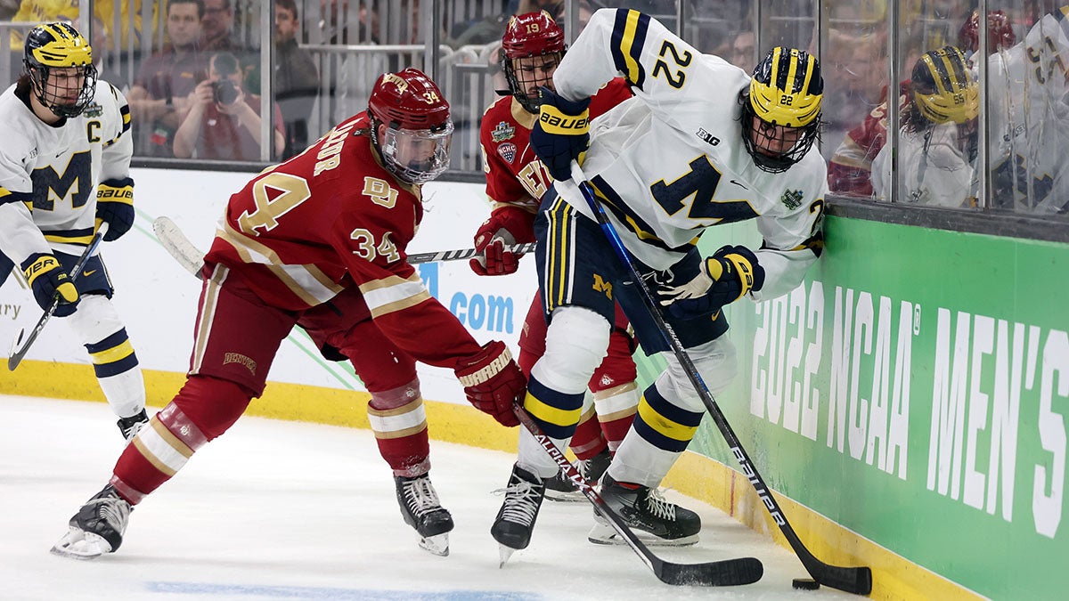 Carter Mazur #34 of the Denver Pioneers defends Owen Power #22 of the Michigan Wolverines during the 2022 Frozen Four semifinal game.