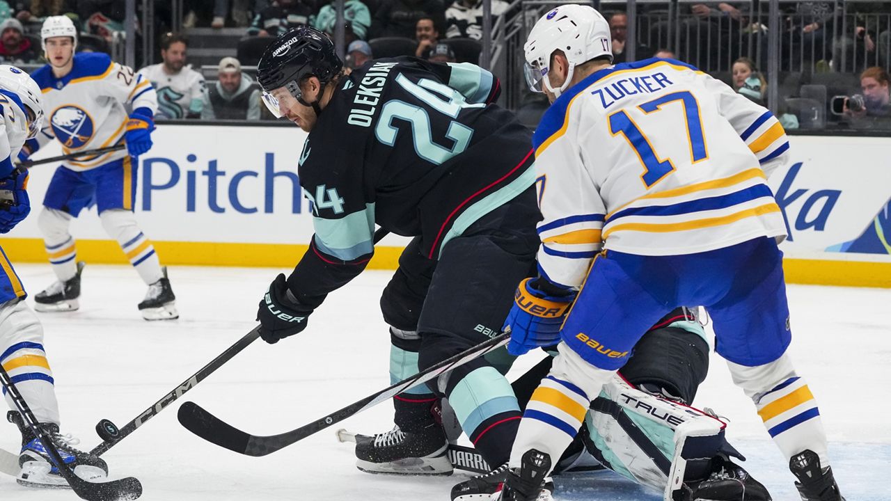 Seattle Kraken defenseman Jamie Oleksiak (24) blocks a shot against the Buffalo Sabres as left wing Jason Zucker (17) looks on during the third period of an NHL hockey game Monday, Jan. 20, 2025, in Seattle. (AP Photo/Lindsey Wasson)