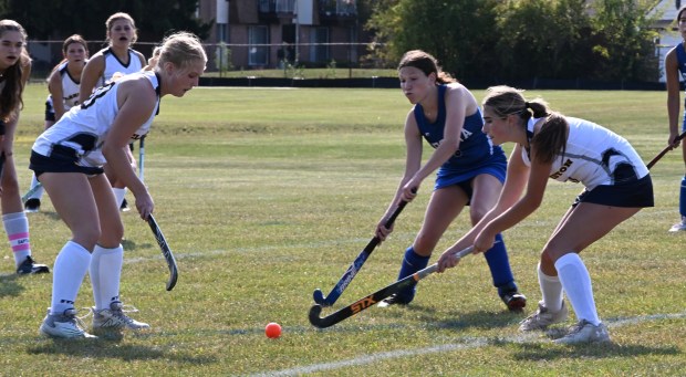 Three players from Clarkston (white) and Warren Regina (blue) converge on the loose ball during Monday's non-league game in Warren on Sept. 8, 2025 (DAN STICKRADT -- MediaNews Group)