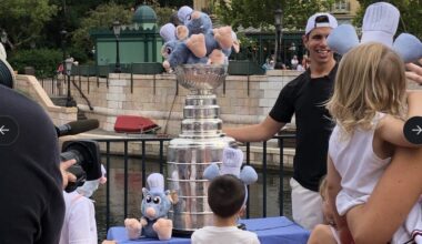 A man and children stand by a Stanley Cup filled with Remy plushies from Ratatouille at an EPCOT outdoor event.