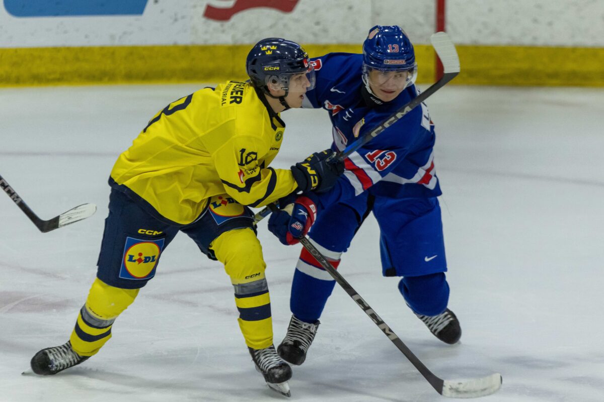 USA’s defenceman Lukas Fischer (13) battles for position with Sweden's forward Victor Eklund (18) during the first period of the 2024 World Junior Summer Showcase at USA Hockey Arena.