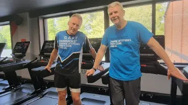 Gary Shaughnessy is standing smiling at the camera wearing is sports attire.