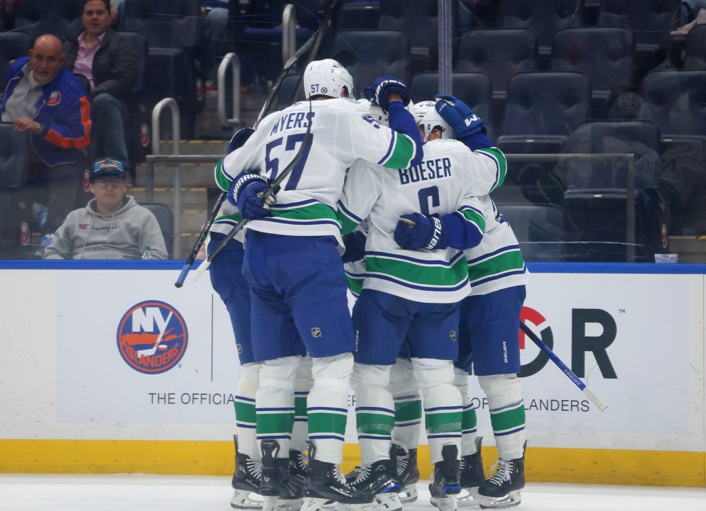 Vancouver Canucks hockey players huddle together on the ice.