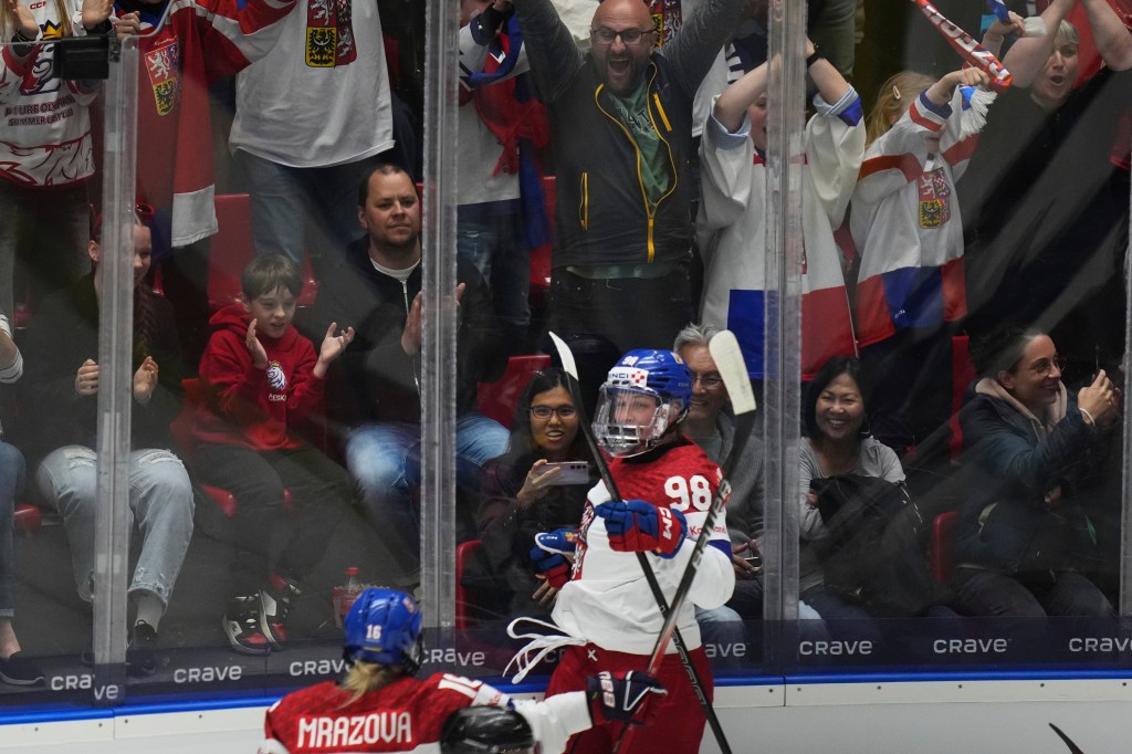Hockey player celebrating a goal with fans in the stands.