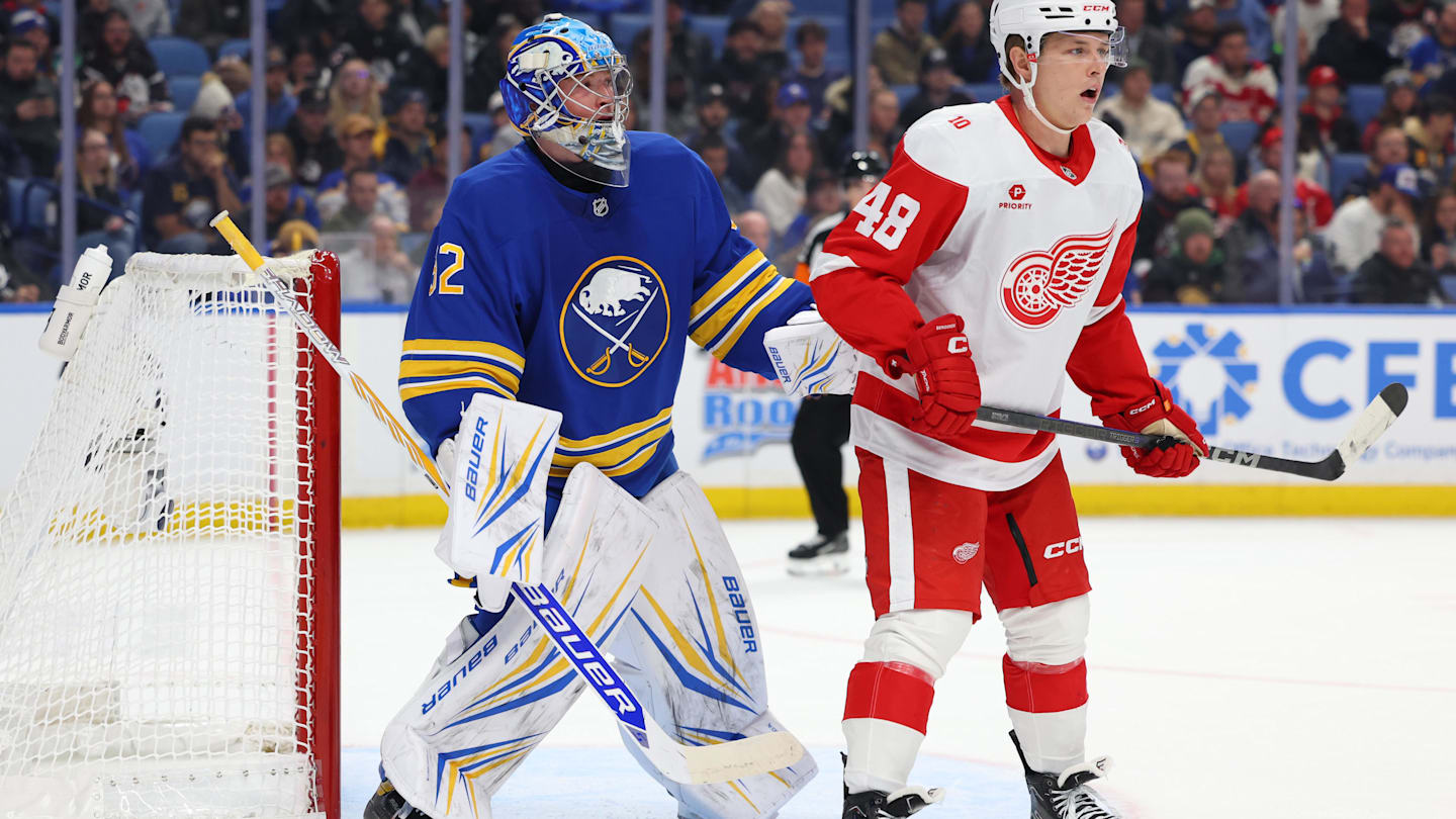 Oct 22, 2025; Buffalo, New York, USA;  Buffalo Sabres goaltender Colten Ellis (92) and Detroit Red Wings right wing Jonatan Berggren (48) look for the puck during the first period at KeyBank Center. Mandatory Credit: Timothy T. Ludwig-Imagn Images