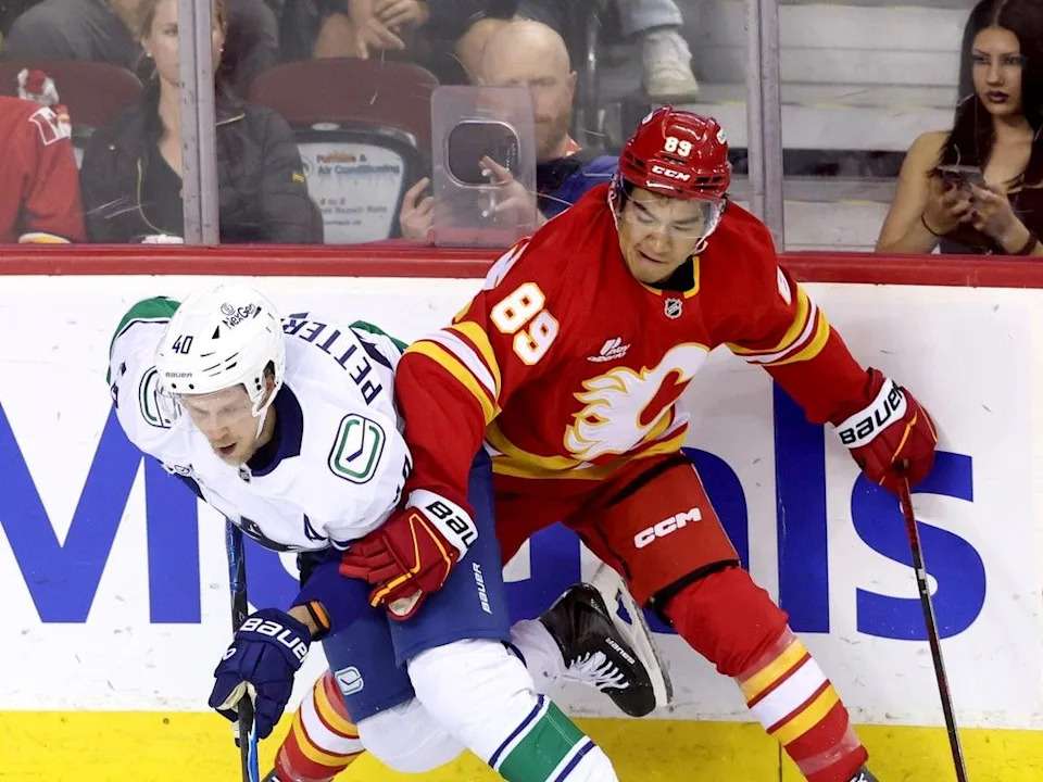  Calgary Flames defenceman Zayne Parekh battles Vancouver Canucks forward Elias Pettersson at the Scotiabank Saddledome on Wednesday, Oct. 1, 2025.