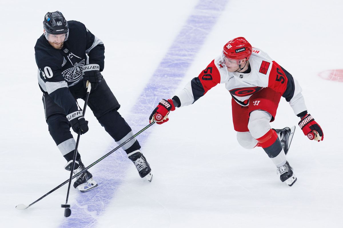 Los Angeles Kings RW Joel Armia (40) and Carolina Hurricanes LW Eric Robinson (50) fight for the puck during an NHL Los Angeles Kings against the Carolina Hurricanes game at the Crypto.com Arena on October 18, 2025 in Los Angeles, California.