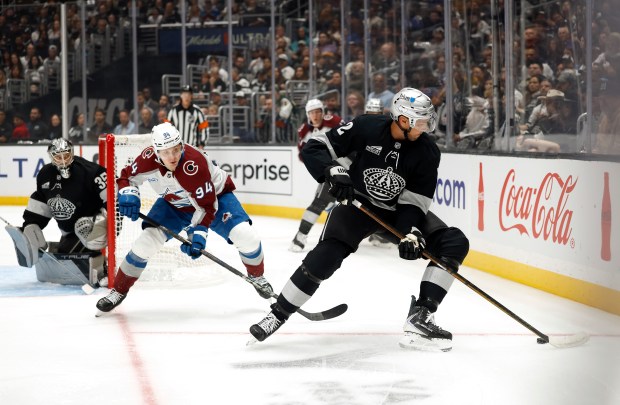The Kings’ Brian Dumoulin, right, skates with the puck as...
