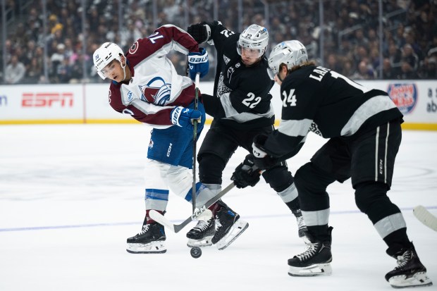 Colorado Avalanche defenseman Sam Malinski, left, vies for the puck...