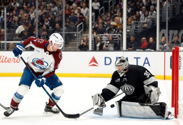Kings goaltender Darcy Kuemper, right, makes a save in front...