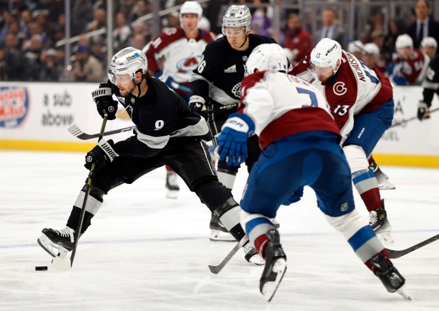 The Kings’ Adrian Kempe, left, skates with the puck during...