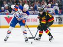 Connor McDavid and Elias Pettersson battle for the puck in the first period