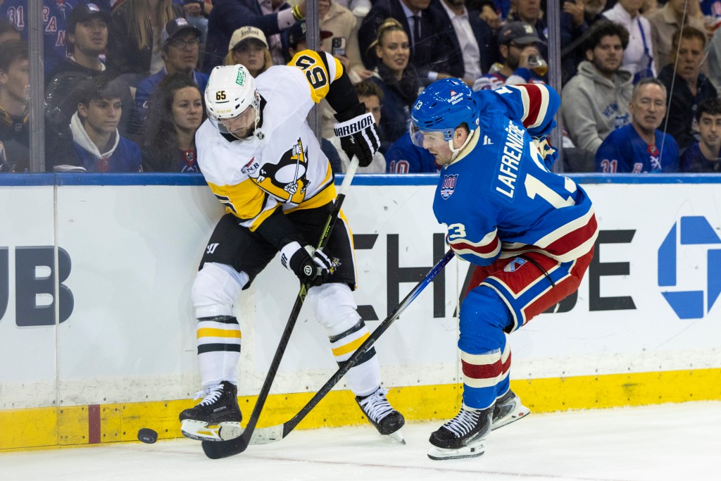 Pittsburgh Penguins defenseman Erik Karlsson (65) and New York Rangers left wing Alexis Lafrenière (13) fight for possession in the third period at Madison Square Garden, Tuesday, Oct. 7, 2025, in New York, NY. (