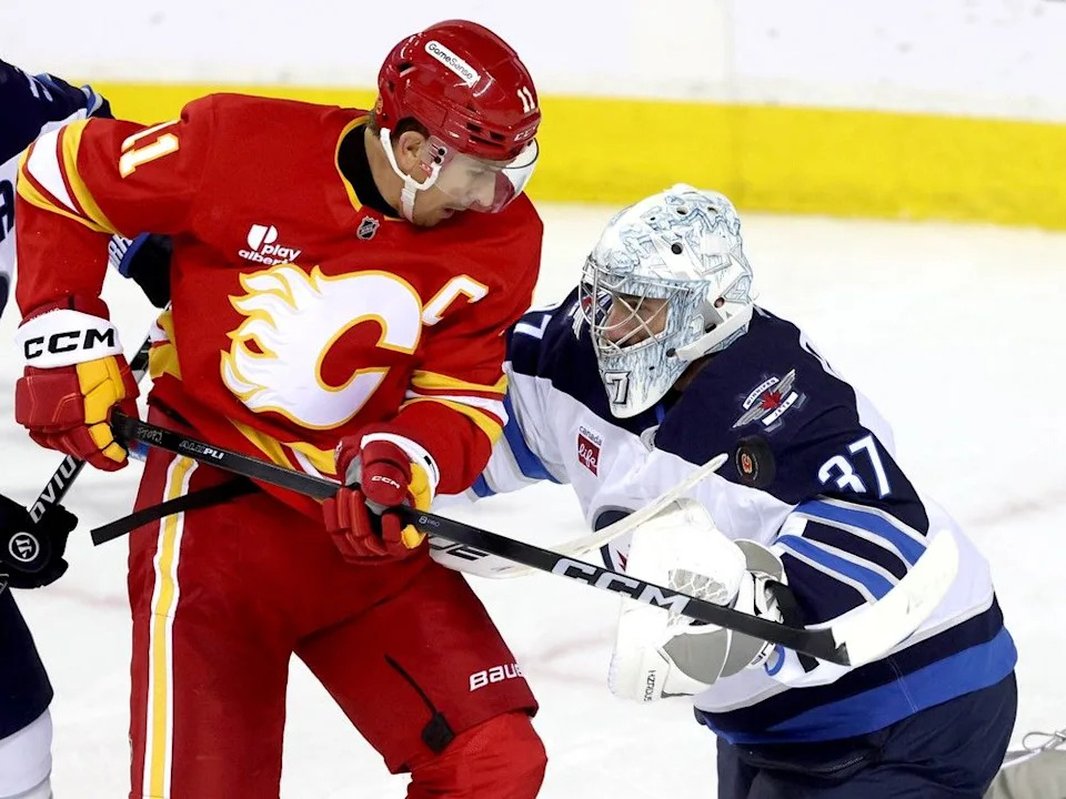 Flames forward Mikael Backlund battles Jets goaltender Connor Hellebuyck on Friday.