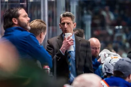 Oilers' head coach Kris Knoblauch confers with coaching staff behind the bench during a road-game
