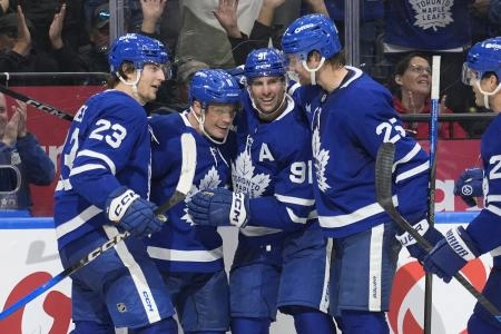 Oct 28, 2025; Toronto, Ontario, CAN; Toronto Maple Leafs forward Matthew Knies (23) and forward John Tavares (91) and defenseman Brandon Carlo (25) congratulate forward Max Domi (11) on scoring the game winning goal against the Calgary Flames during the third period at Scotiabank Arena