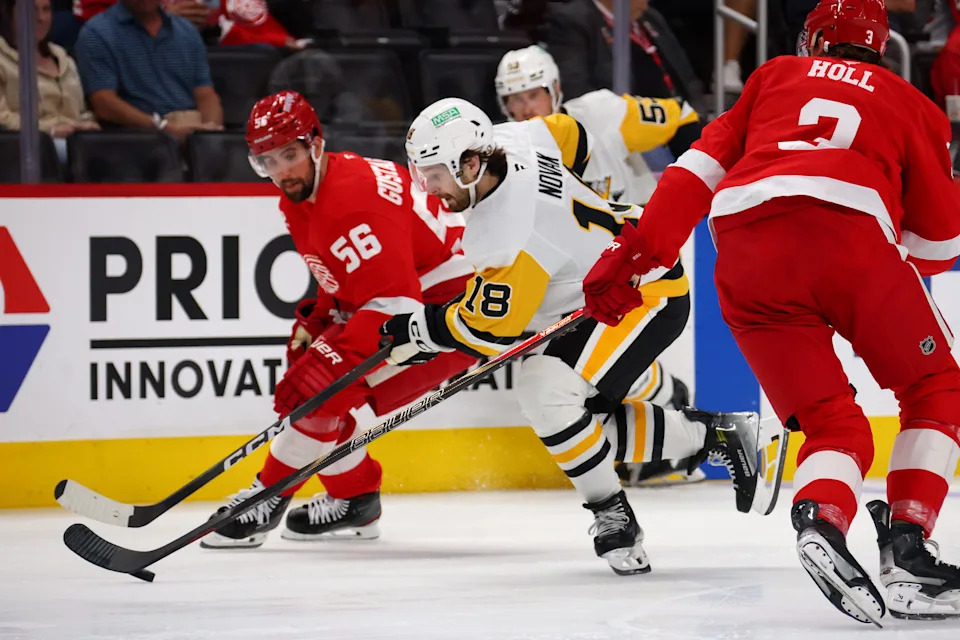 Tommy Novak of the Pittsburgh Penguins splits the defense of Justin Holl and Erik Gustafsson of the Detroit Red Wings during a preseason game at Little Caesars Arena in Detroit on Monday, Sept. 29, 2025.
