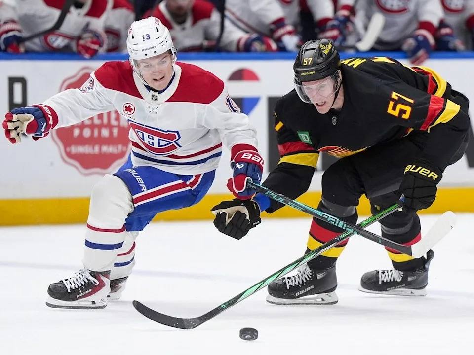  Canadiens’ Cole Caufield (13) and Canucks’ Tyler Myers (57) vie for the puck in Vancouver on Saturday, Oct. 25, 2025.