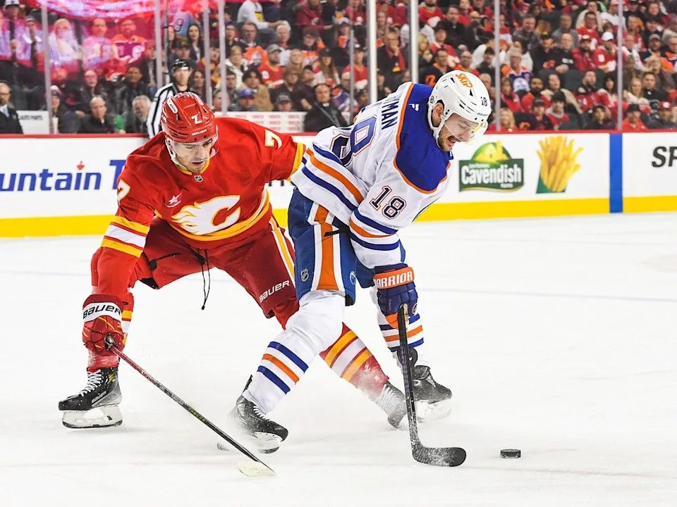  Oilers forward Zach Hyman carries the puck against Flames defenceman Kevin Bahl during firstperiod at Scotiabank Saddledome on November 3, 2024 in Calgary, Alberta, Canada.