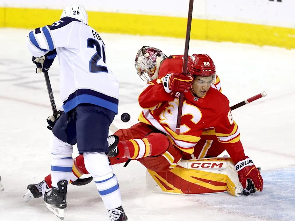Flames goaltender Dustin Wolf and prospect Zayne Parekh defend against Jets prospect Parker Ford on Friday.